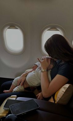 a woman holding a baby while sitting on an airplane