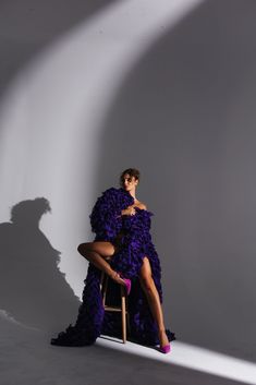 a woman in a purple dress sitting on a chair