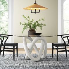 a dining room table with chairs and a vase on top of it, in front of two windows