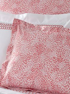 two red and white pillows sitting on top of a bed next to eachother