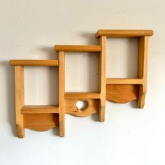 three wooden shelves on the wall, one with a heart shaped hole in the middle