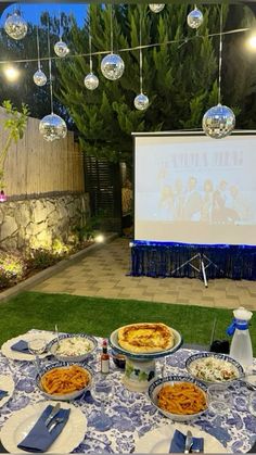 an outdoor movie is set up on the lawn with food and drinks in front of it