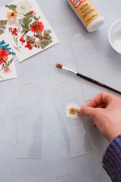 someone is painting flowers with acrylic paint on the table next to some cards