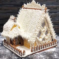 a gingerbread house with icing on the roof and snow on the ground around it