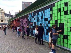 people are standing in front of a wall that has many different colored squares on it