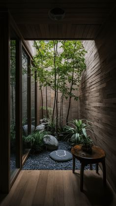 the inside of a house with wooden walls and plants on the floor, along with a small table