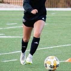 a young woman kicking a soccer ball on a field