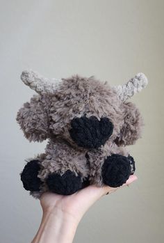 a hand holding a small stuffed animal with horns