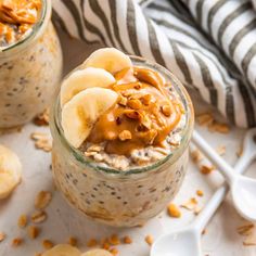 two jars filled with oatmeal and bananas on top of a white table