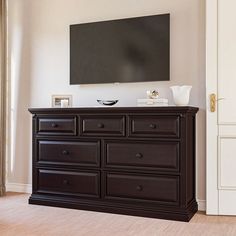 a black dresser with a flat screen tv mounted above it