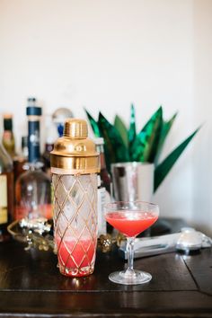 a table topped with a glass filled with liquid and a shaker on top of it