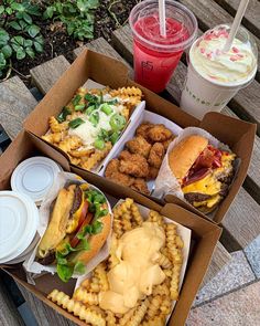 two boxes filled with food sitting on top of a picnic table next to drinks and ice cream