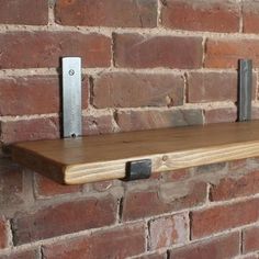 a wooden shelf with metal handles on a brick wall