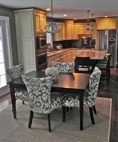 a dinning room table and chairs in front of an open kitchen with wooden cabinets