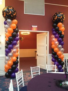 an arch made out of balloons in the middle of a room with tables and chairs