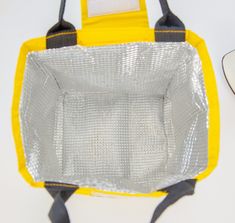 a yellow and gray bag sitting on top of a white table next to a computer mouse