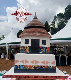 a multi - tiered cake sitting on top of a table in front of tents