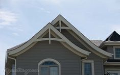 a gray house with white trim on the roof and windows is shown in front of a blue sky