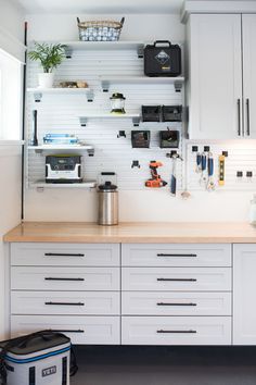 a kitchen with white cabinets and lots of storage space on the wall, including an ice chest