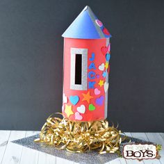 a paper house with gold streamers and confetti on the floor next to it