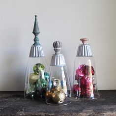 three glass vases with ornaments in them on a table