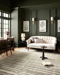 a living room with green walls and furniture in the corner, including a white couch