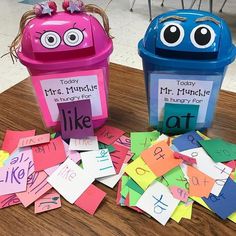 two plastic trash cans sitting on top of a wooden table covered in cut out letters