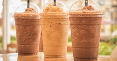 three different types of drinks sitting on a table in front of a window, one with ice cream and the other with chocolate