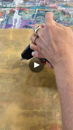 a person is using a pen to paint on a piece of wood with acrylic