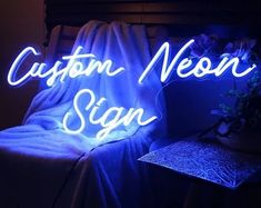 a neon sign that says custom neon signs on the side of a bed in a dark room