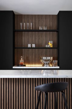 a kitchen with black cabinets and white counter tops, along with a bar stool in front of it