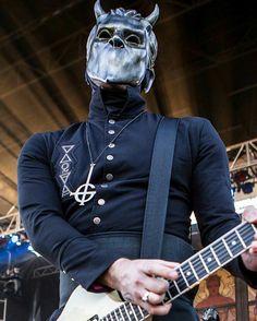 a man wearing a metal mask playing an electric guitar