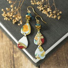 Looking for unique boho jewelry? Don't miss out on these one-of-a-kind floral earrings! Carefully handcrafted from recycled vintage tins, these long teardrop earrings feature floral patterns that add a unique touch. Lightweight and stylish, they are finished with glass beads and hypoallergenic gold plated ear wires. I take great care in crafting my vintage tin earrings, ensuring smooth edges through a meticulous sanding process. Given the vintage materials used, minor imperfections may be present, adding to their charm and uniqueness. These unique earrings measure approximately 2 1/2" long from the top of the wire to the bottom and are about 1/2" wide. Feel free to reach out if you have any questions at all. Thank you for visiting my shop, and be sure to check back often as I'm always crea Free Spirit Jewelry, Tin Jewelry, Tin Earrings, Felt Jewelry, Boho Chic Jewelry, Recycled Jewelry, Vintage Tins, Upcycled Jewelry, Smooth Edges