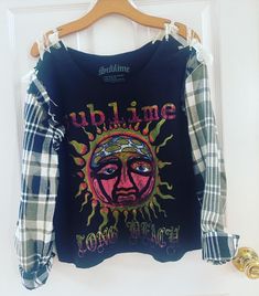 a black shirt with an image of a sun on the front, and plaid sleeves