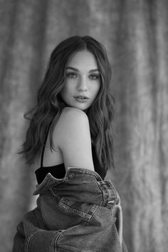 a black and white photo of a woman with her arms folded over her chest, wearing jeans