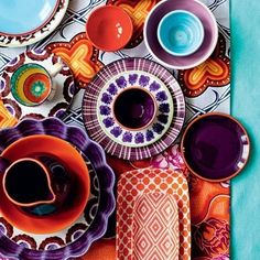 an assortment of colorful dishes and cups on a table with the color scheme in red