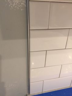 a white tiled wall with blue flooring in a room that is being remodeled and remodeled