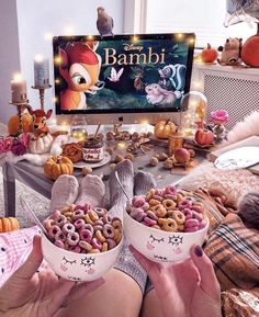 a table topped with bowls filled with donuts next to a computer screen and stuffed animals