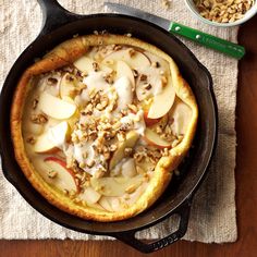 a pan filled with food sitting on top of a wooden table next to a spoon