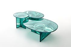 two glass tables sitting next to each other on top of a white table with an abstract design