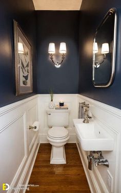 a white toilet sitting under two mirrors in a bathroom