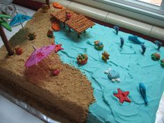 a cake that is shaped like a beach scene with an umbrella and other items on it