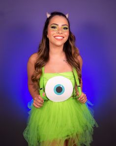 a woman in a green dress with an evil eyeball on her chest and large eyelashes