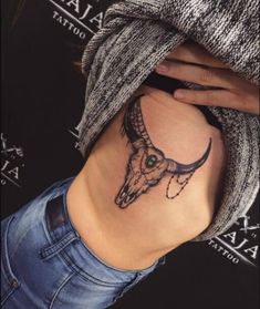 a woman's lower back tattoo with an animal skull and green eyes on her left side