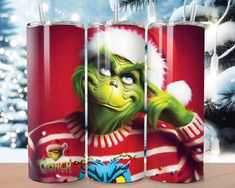 three red tumblers with the grinch character on them in front of a christmas tree