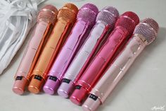 six colorful microphones lined up next to each other on a white counter top with a bag in the background