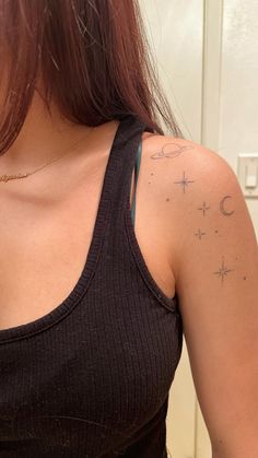 a woman with a star and moon tattoo on her left arm, wearing a black tank top