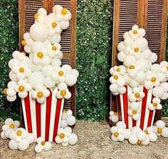 two red and white popcorn buckets filled with balloons