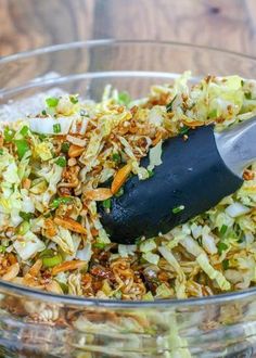 a glass bowl filled with coleslaw slaw and a black plastic spatula