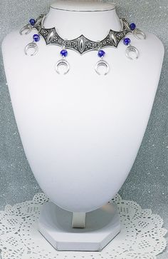 Victorian Gothic metal choker with crescent moon charms and blue crystal beads, ornate metal necklace, Victorian jewelry, Gothic jewelry A beautifully ornate gothic silver metal choker with Victorian crescent moon charms and blue faceted crystal beads. It measures approx. 11 inches in length and has lobster clasp fastening and an extension chain, so that it can be adjusted to fit the neck. The choker is made up of 7 silver toned metal ancient style sections that have intricate detailing. A marve Gothic Festival Jewelry With Moon Charm, Crescent Metal Jewelry For Festivals, Metal Crescent Jewelry For Festivals, Gothic Blue Metal Jewelry, Handmade Gothic Blue Necklace, Metal Crescent Shaped Festival Jewelry, Crescent-shaped Metal Jewelry For Festivals, Blue Gothic Metal Jewelry, Handmade Blue Gothic Necklace